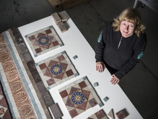 Conservator Kirsten Strachan working on a large tiled floor from the waiting room at Grantham Railway Station.