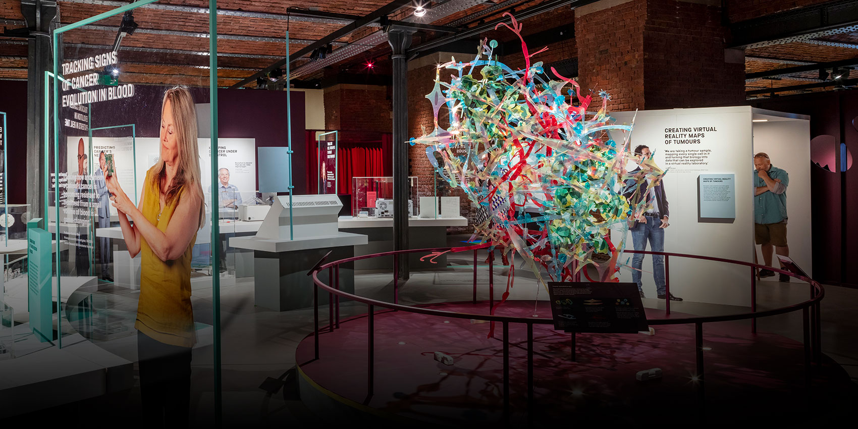 Gallery space with various exhibits and a colourful sculpture in the centre